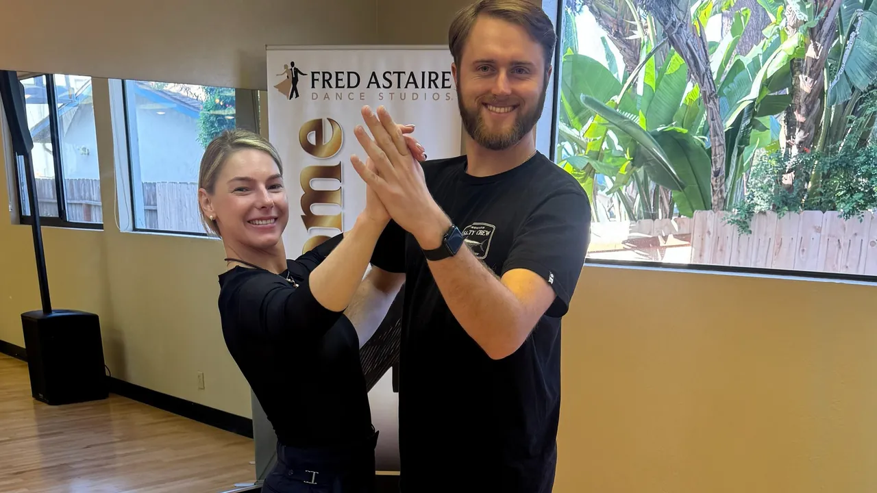 Two adults hold a ballroom frame together in the Solana Beach studio.