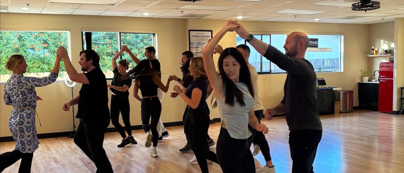 Adults dance in pairs across the studio floor.